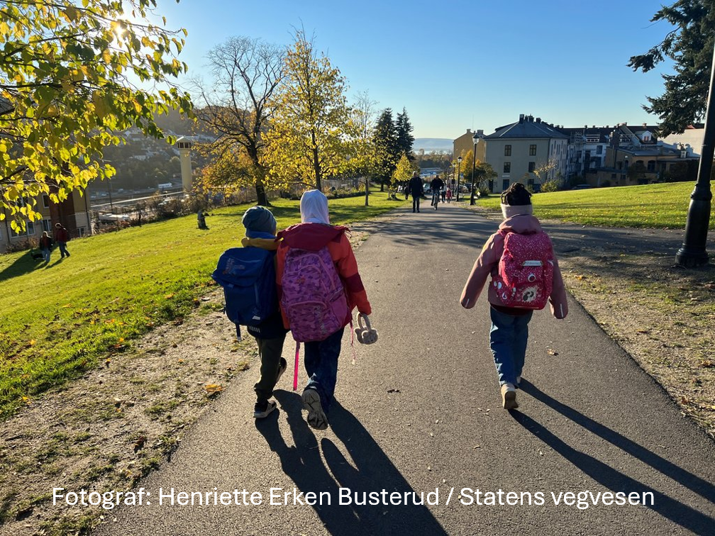 Solrik høstdag med barn som går mot skole/bygninger